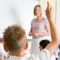 Classroom with boy raising his had for the teacher